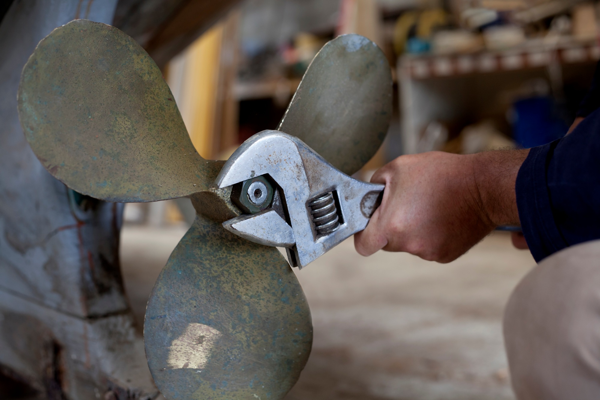 Man tightening boat propeller in workshop